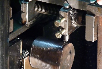 A round, single point, cutting tool taking a cut on the crankshaft. The screw thread, in view, controls the cross traverse.
