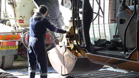 Loading the grab with concrete from the mixer lorry.